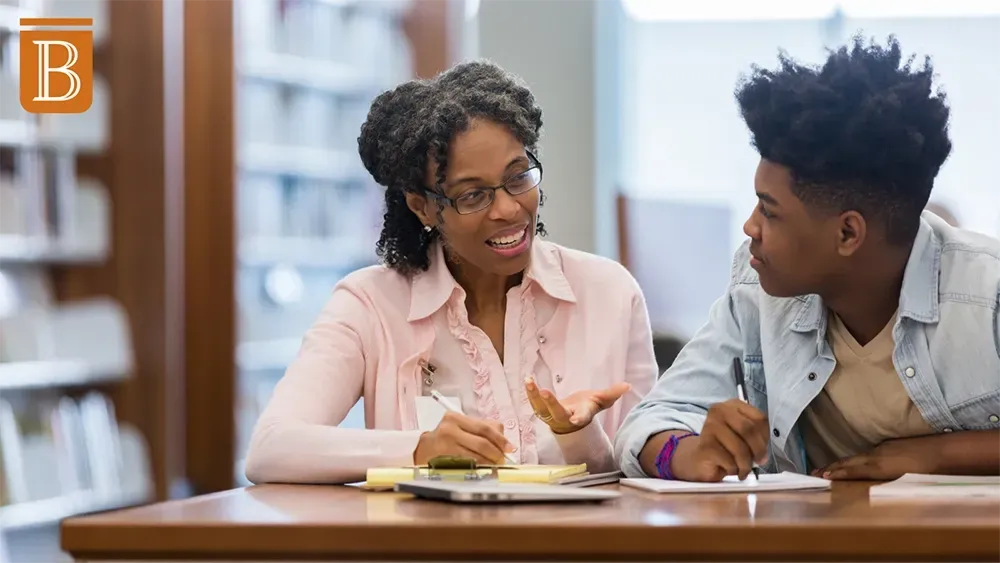 student and teacher working at a desk