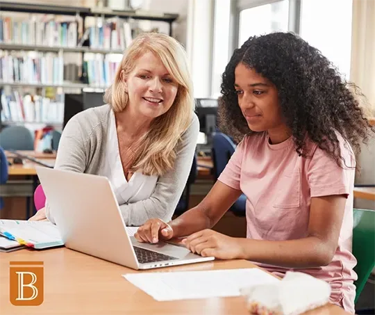 teacher and student working at a desk