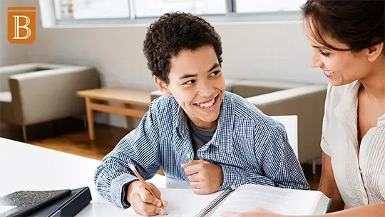 student working at a desk with a teacher