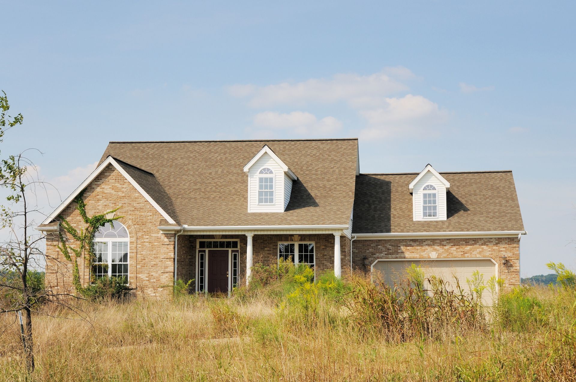 A brick house sits in the middle of a field