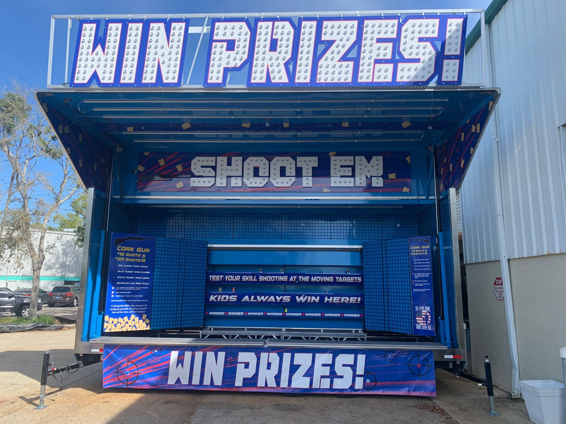 Two children eating a large, blue cotton candy outside a prize booth.