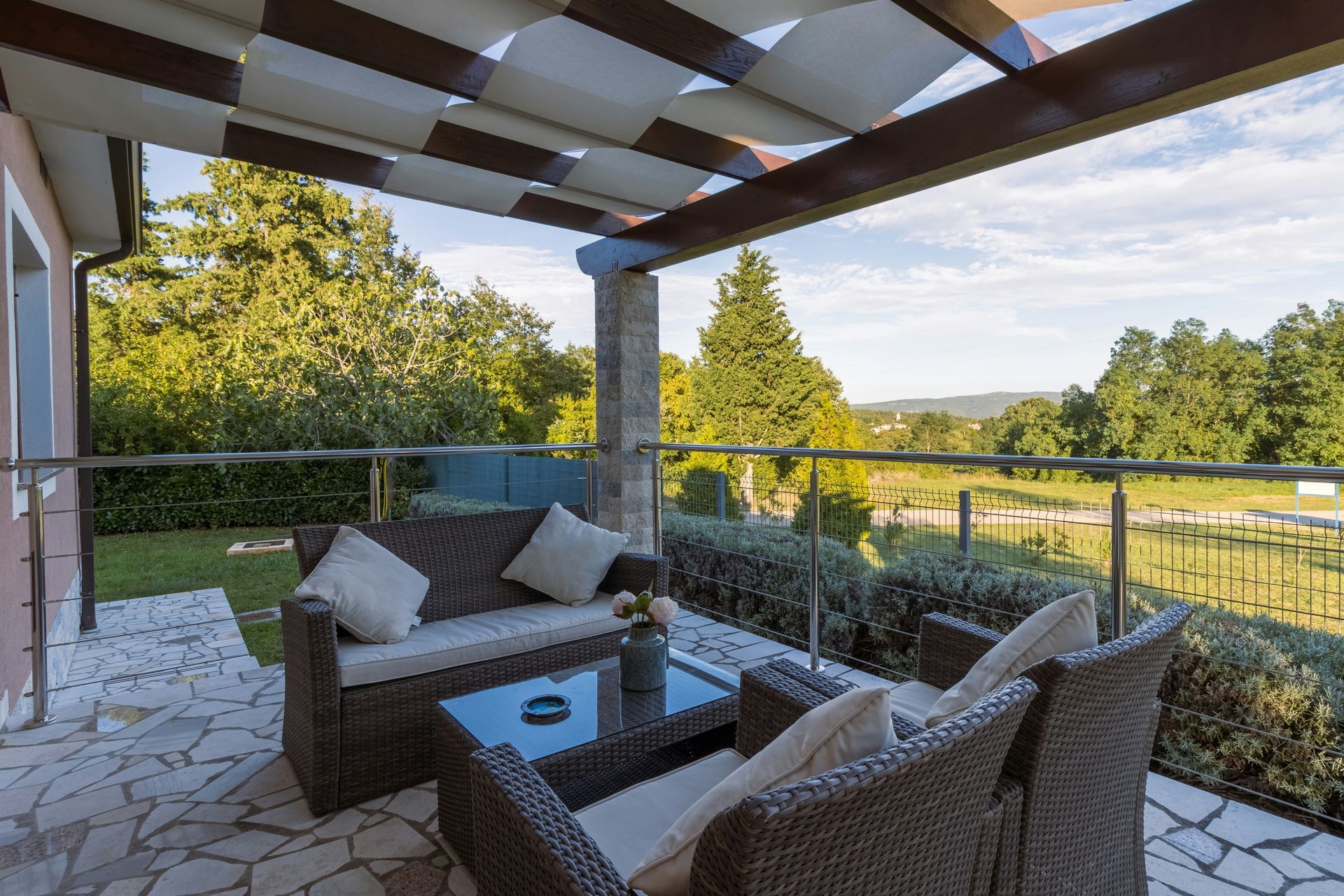 A patio with chairs , tables and a vase of flowers.