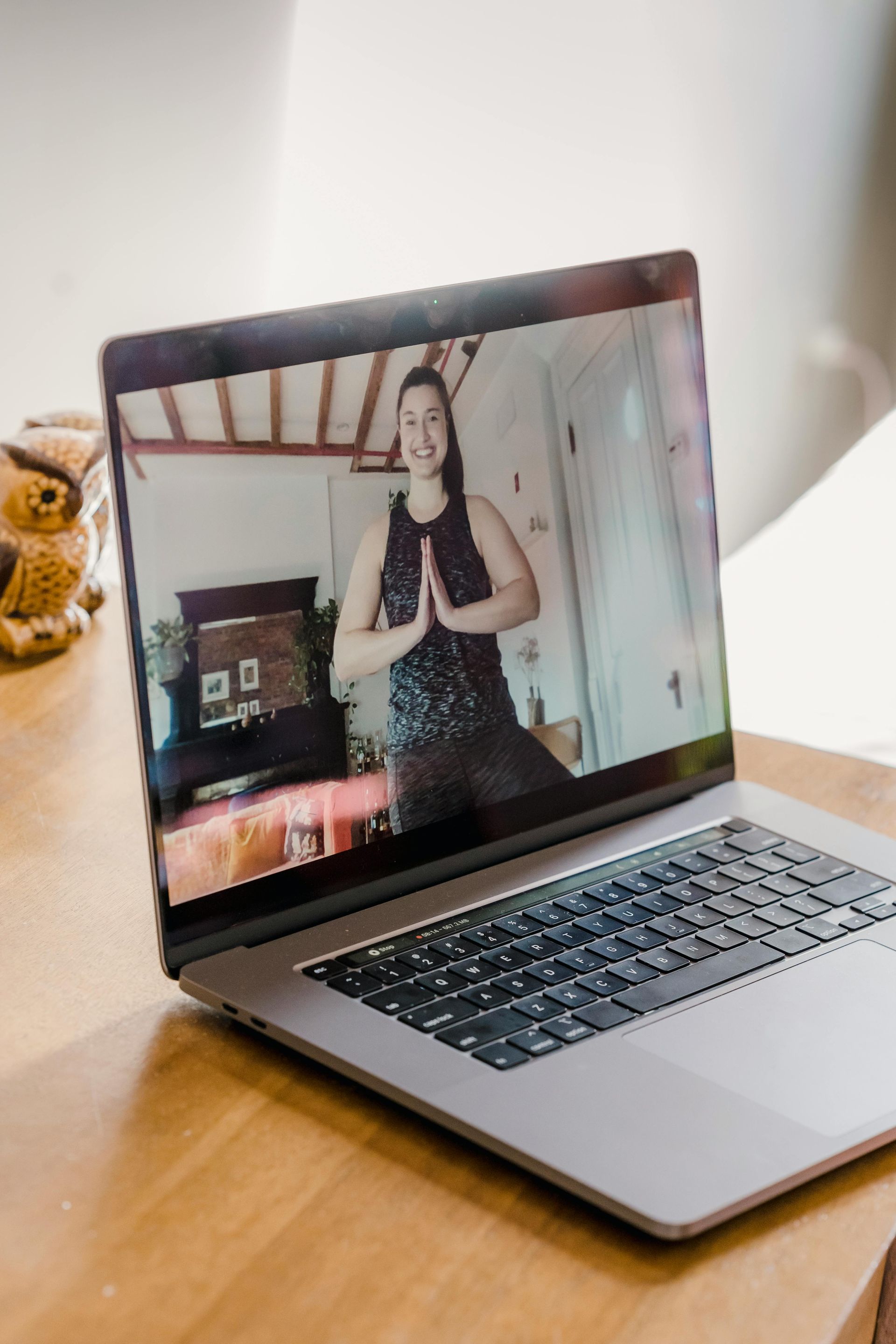 Laptop on table showing a woman leading a yoga class; smiling.