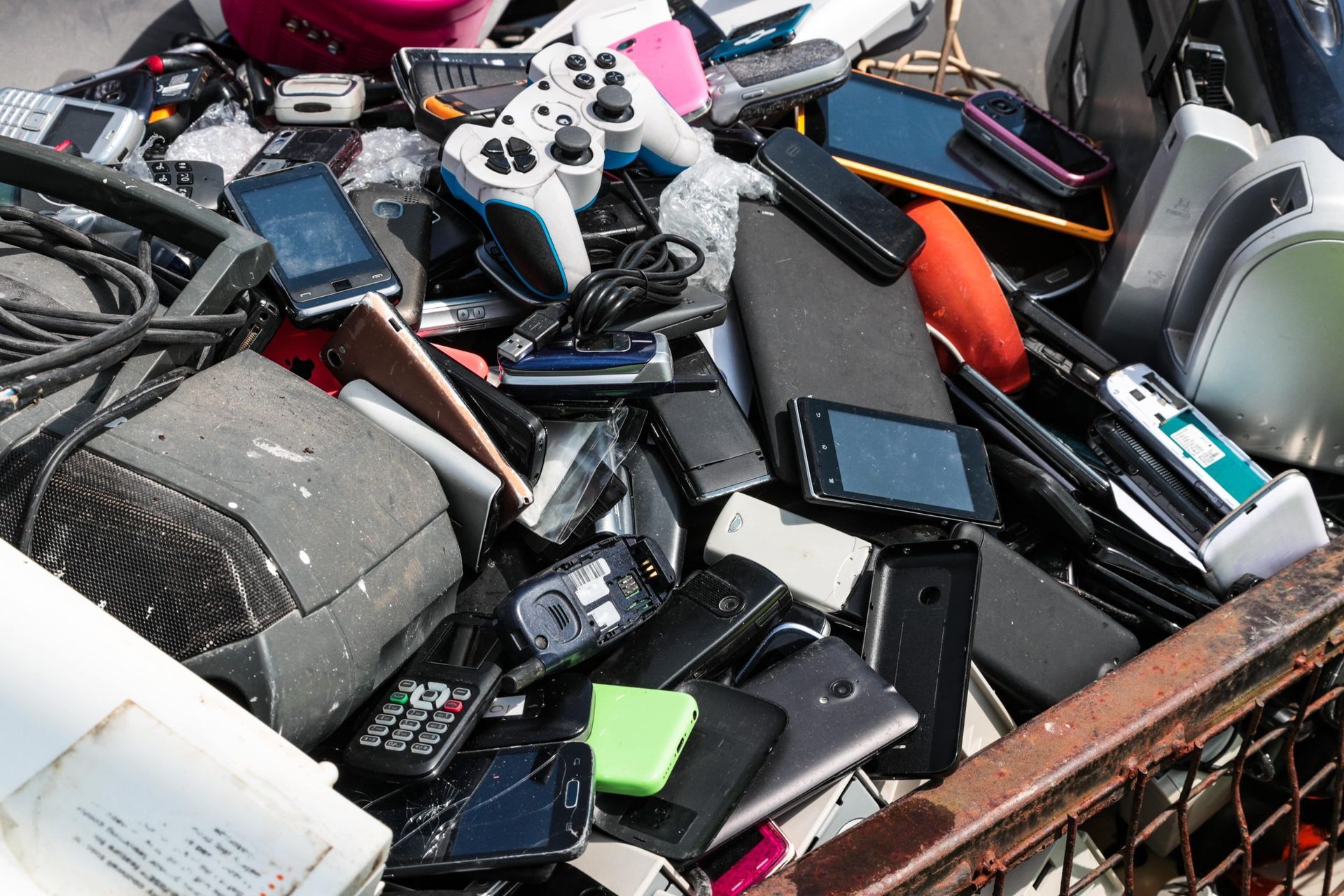A pile of old electronics including cell phones and remote controls
