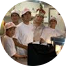 A group of people are standing in a circle in a kitchen.