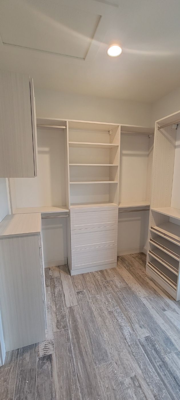 a walk in closet with lots of shelves and drawers .