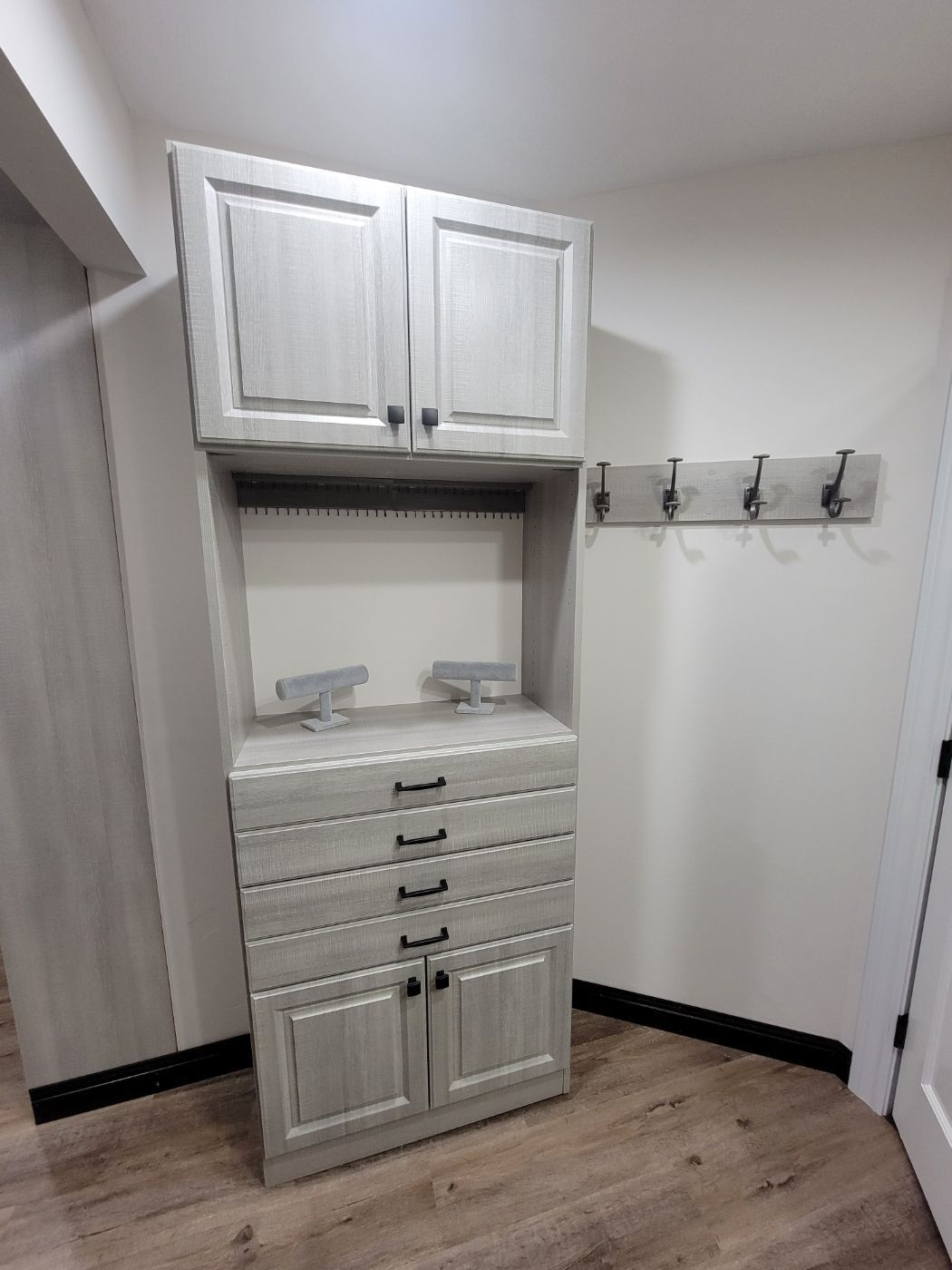 a corner of a room with a dresser and hooks on the wall .