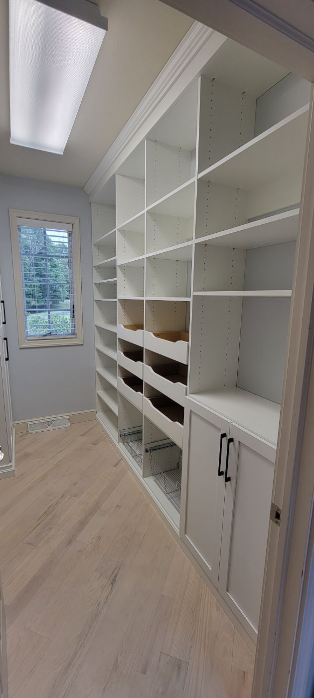 a walk in closet with lots of shelves and cabinets .