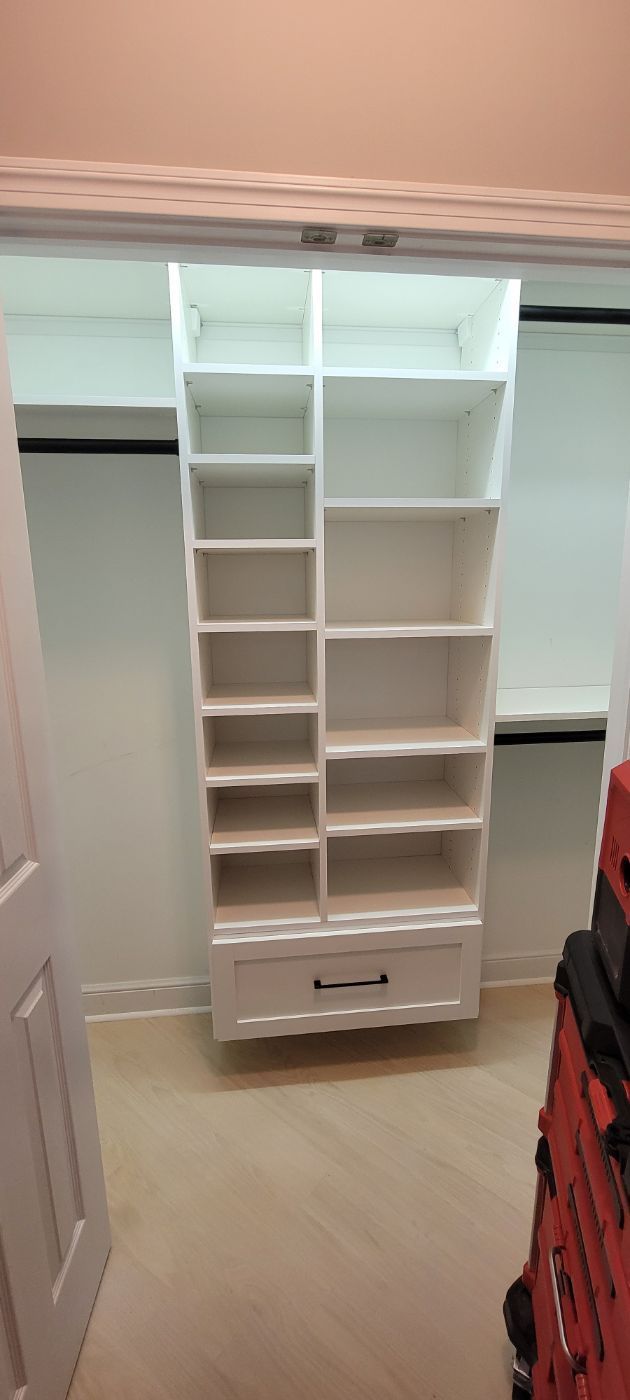 a walk in closet with lots of shelves and drawers .