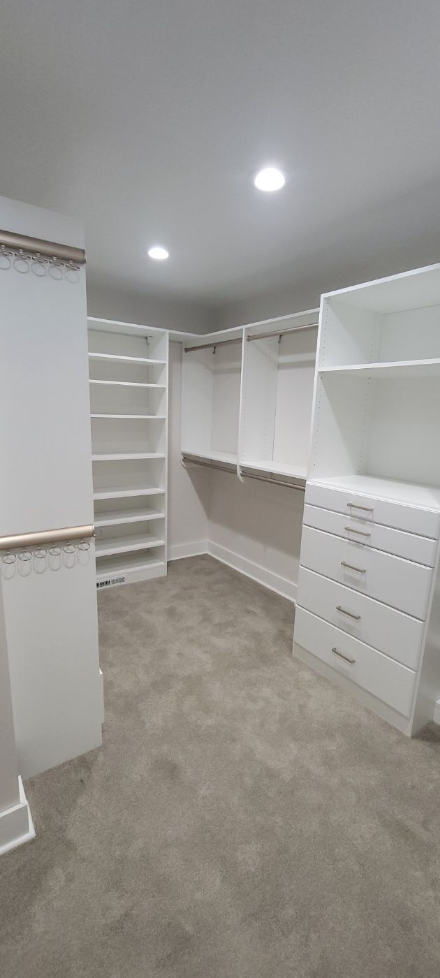a large walk in closet with lots of shelves and drawers .