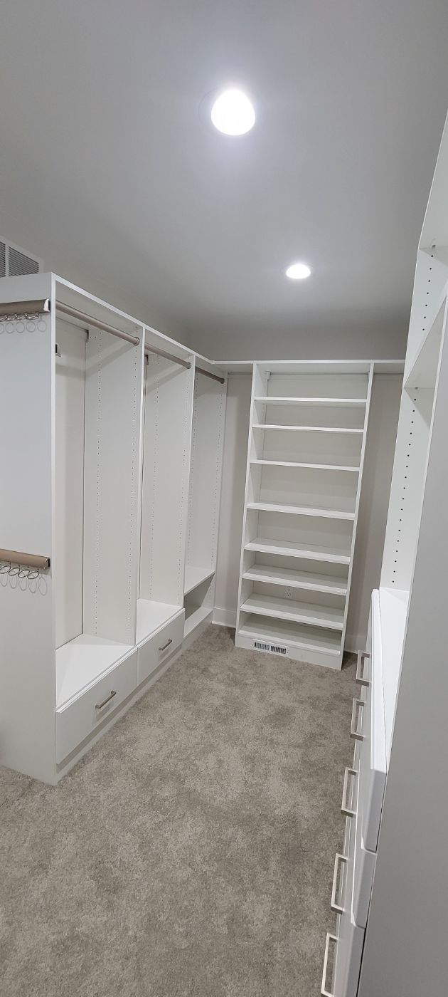 a walk in closet with lots of shelves and drawers .