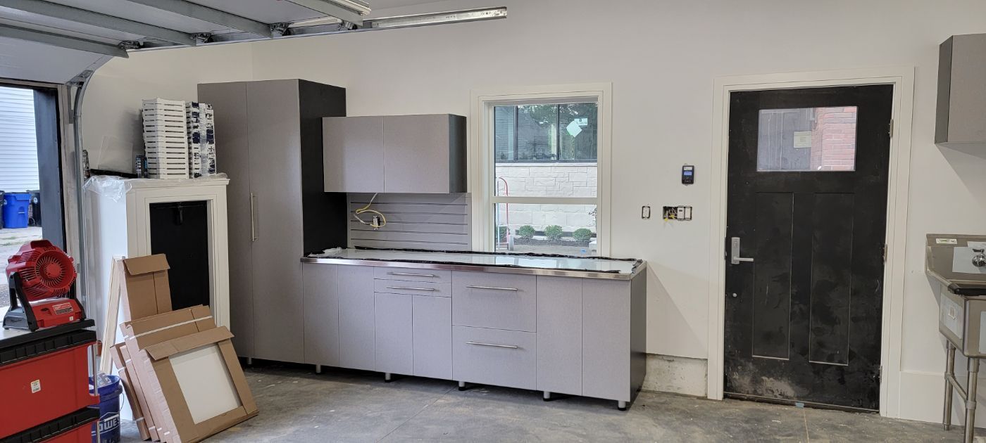 a garage with a sink , cabinets , and a black door .