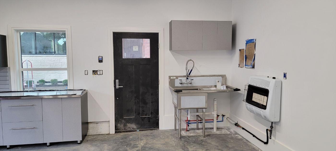 a kitchen with a sink , cabinets , and a black door .