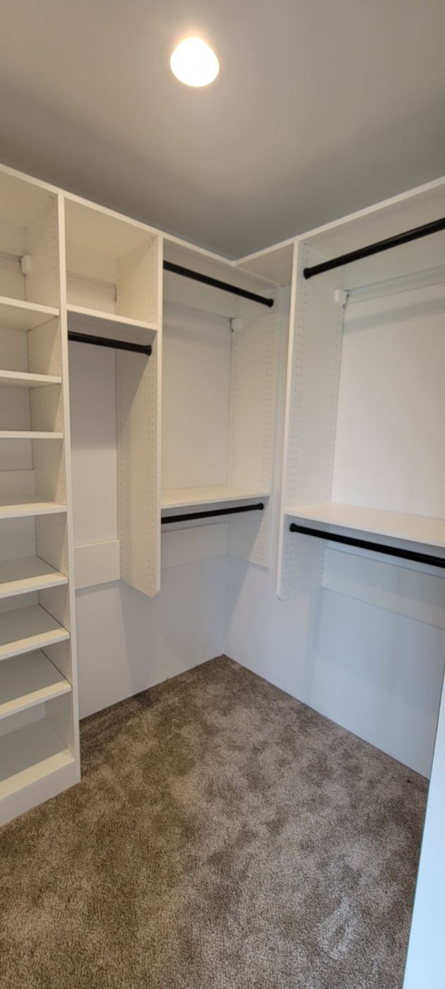 a walk in closet with white shelves and a carpeted floor .
