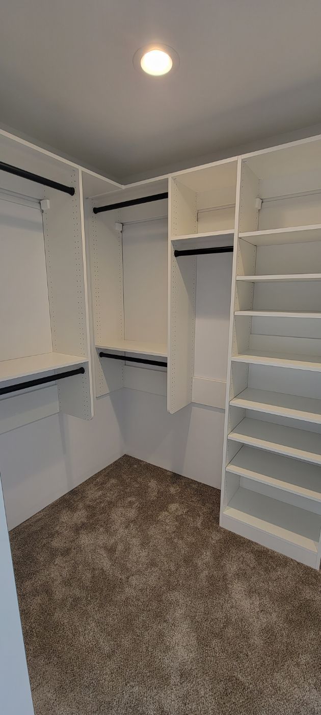 a walk in closet with lots of shelves and clothes racks .