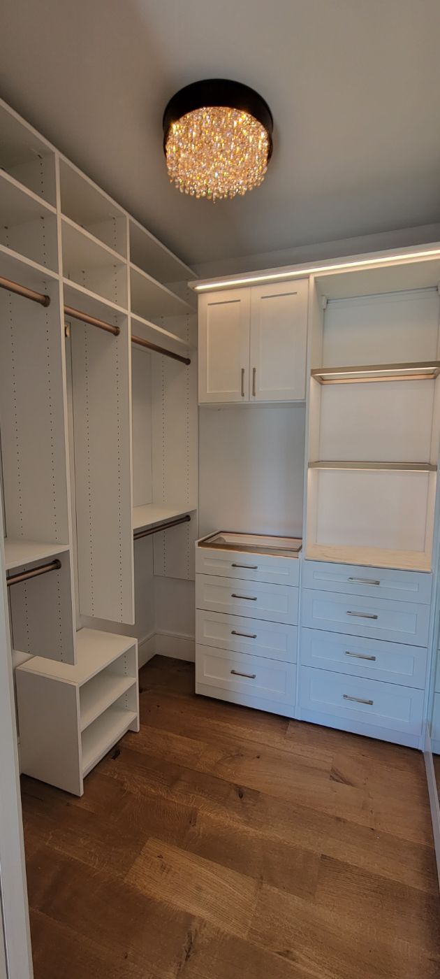 a walk in closet with lots of shelves and drawers and a ceiling light .