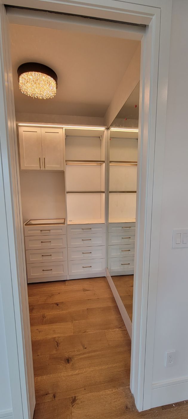 a walk in closet with lots of shelves and drawers and a mirror .