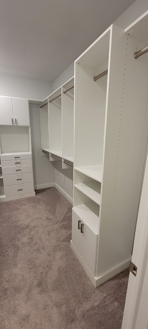 a walk in closet with lots of shelves and drawers .