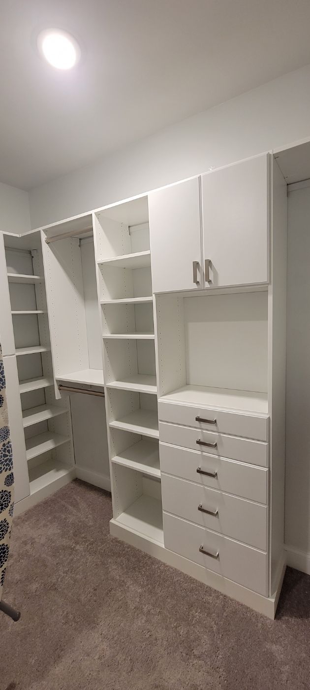 a walk in closet with lots of shelves and drawers .