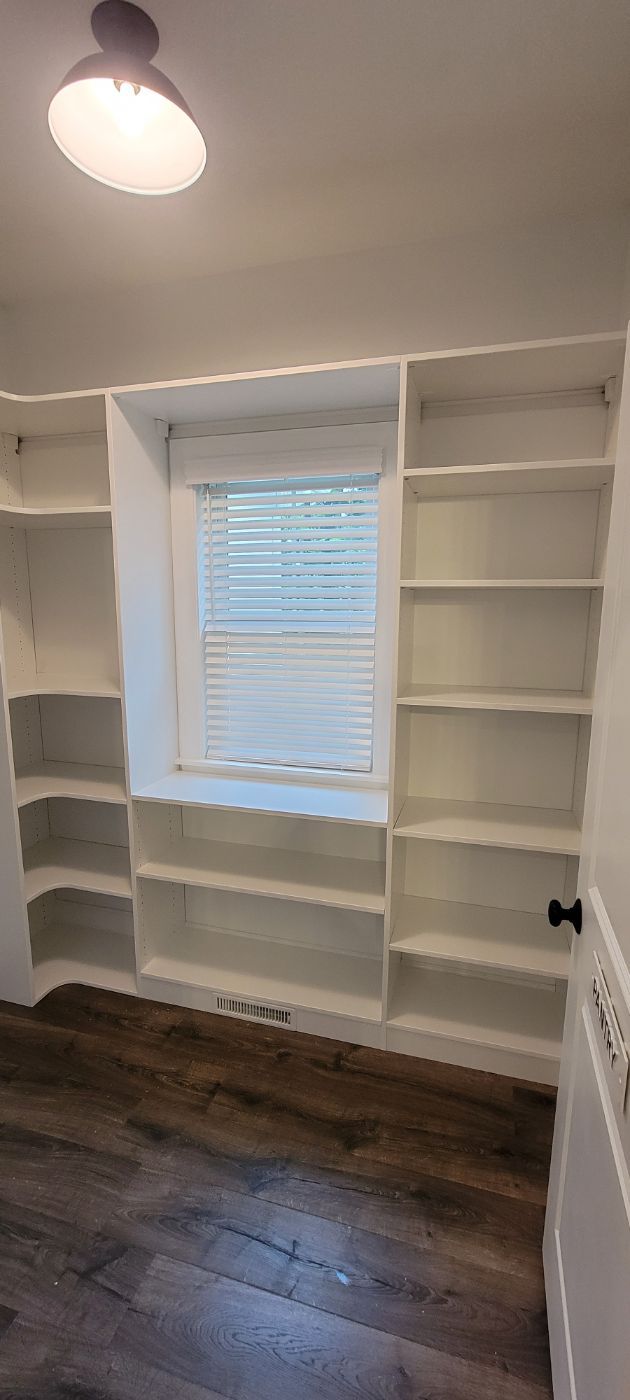 a room with a lot of shelves and a window .