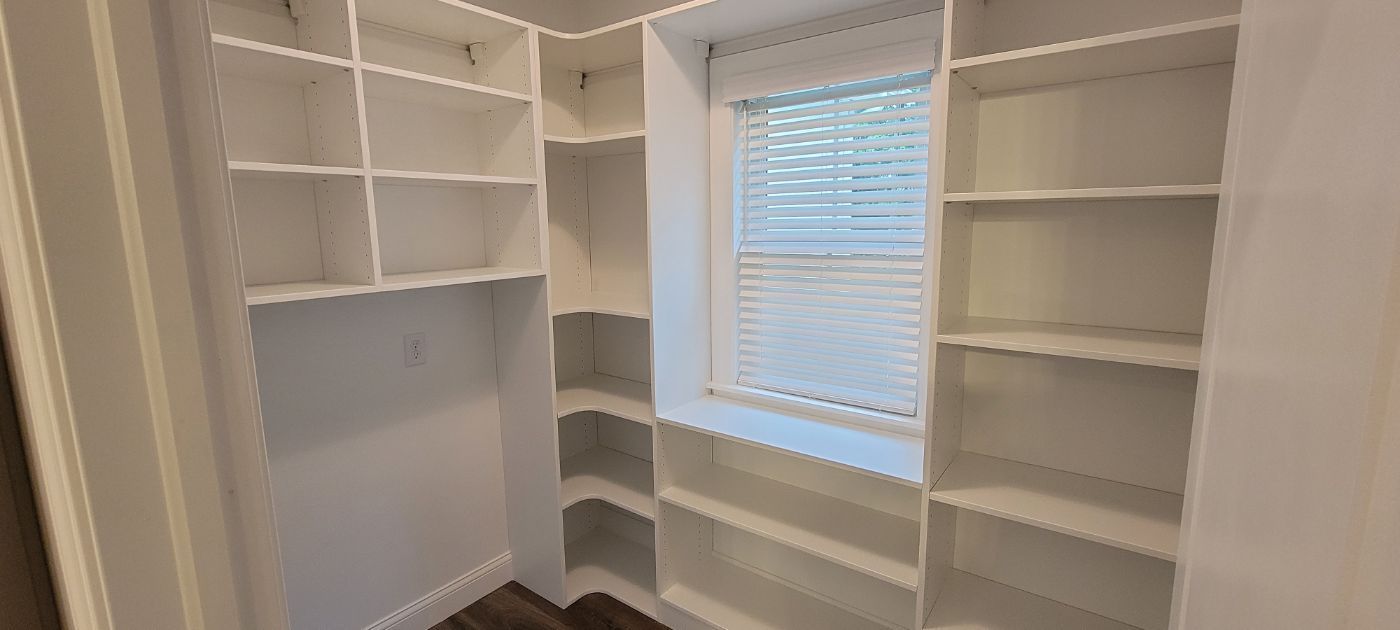 a walk in closet with lots of shelves and a window .
