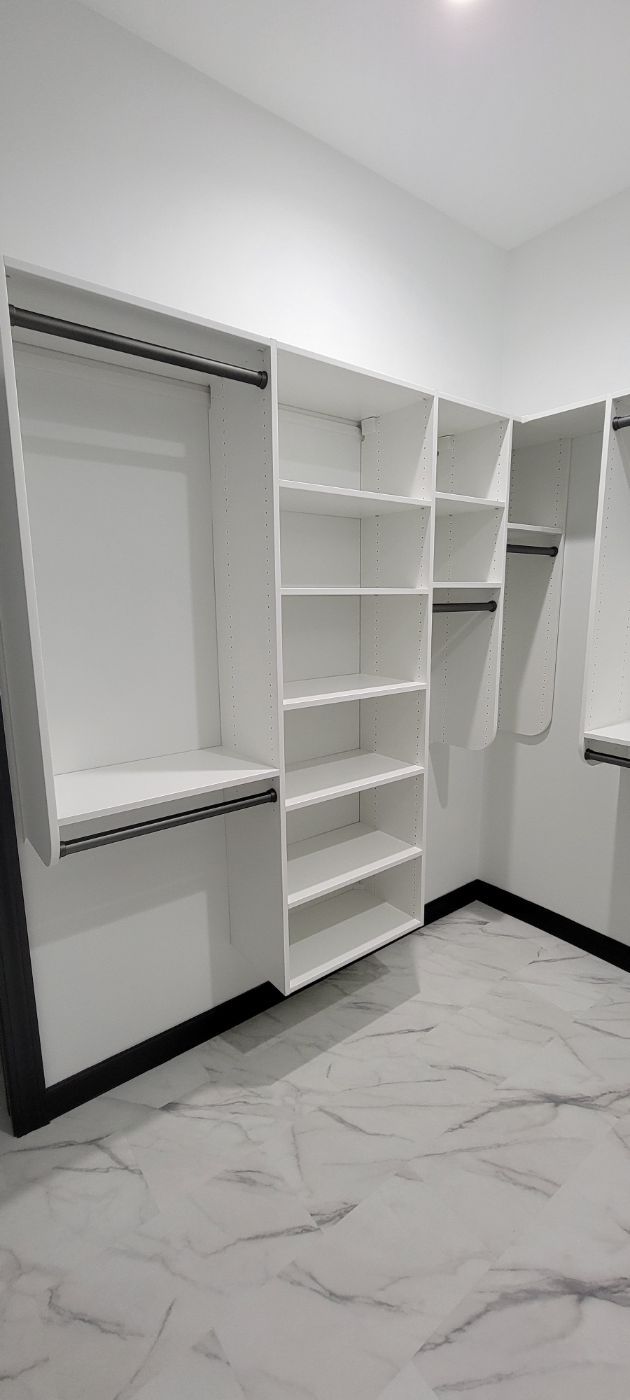 a walk in closet with lots of shelves and hanging clothes .