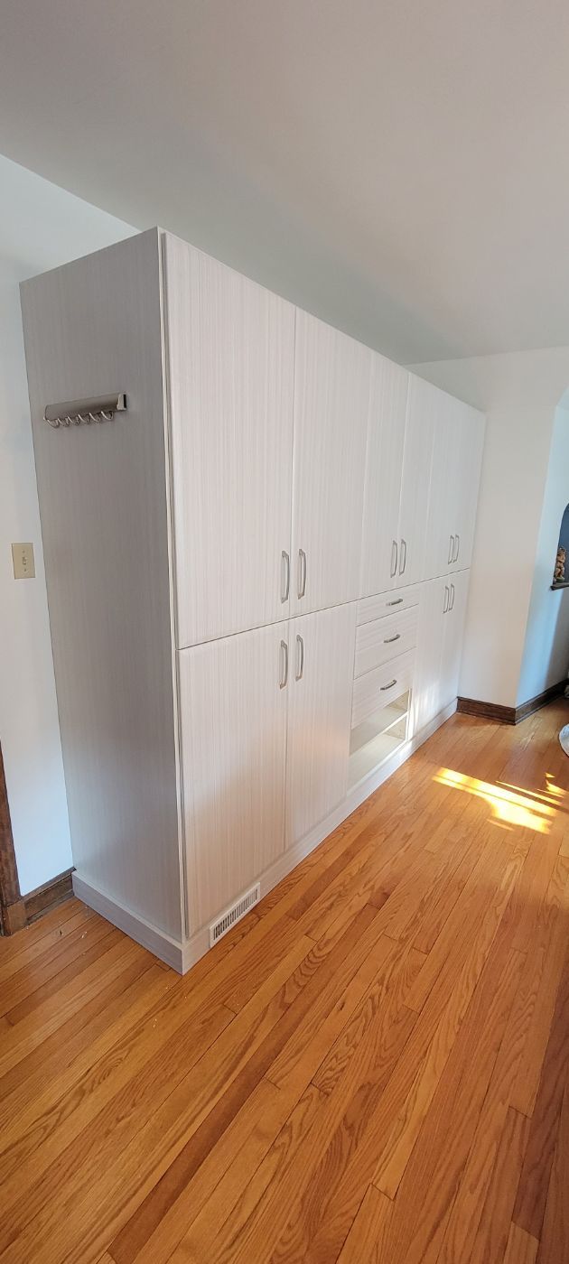 a room with hardwood floors and white cabinets .
