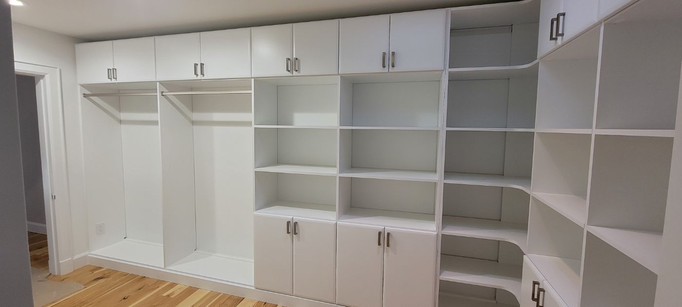 a large walk in closet with lots of shelves and cabinets .