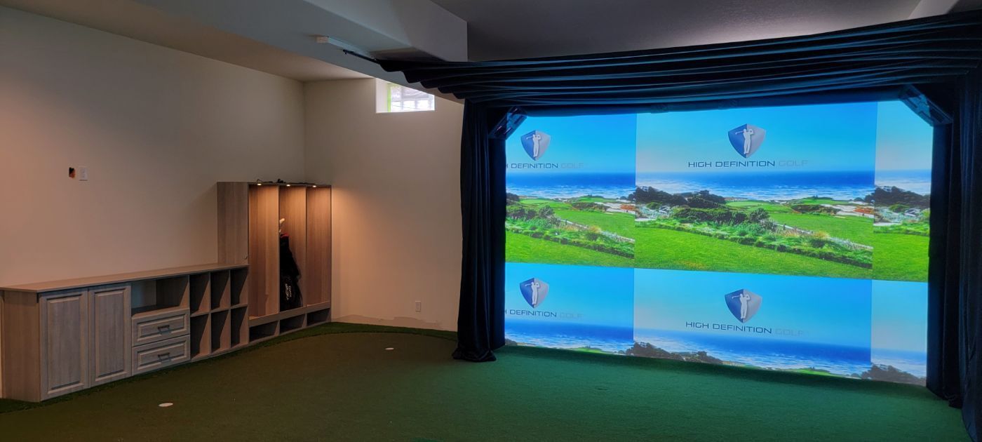 a room with a large screen on the wall that shows a golf course .
