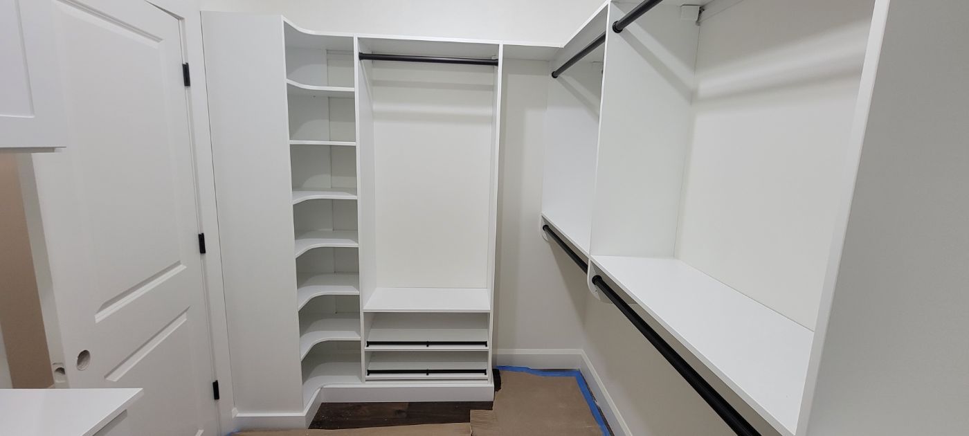 a walk in closet with lots of shelves and hanging racks .