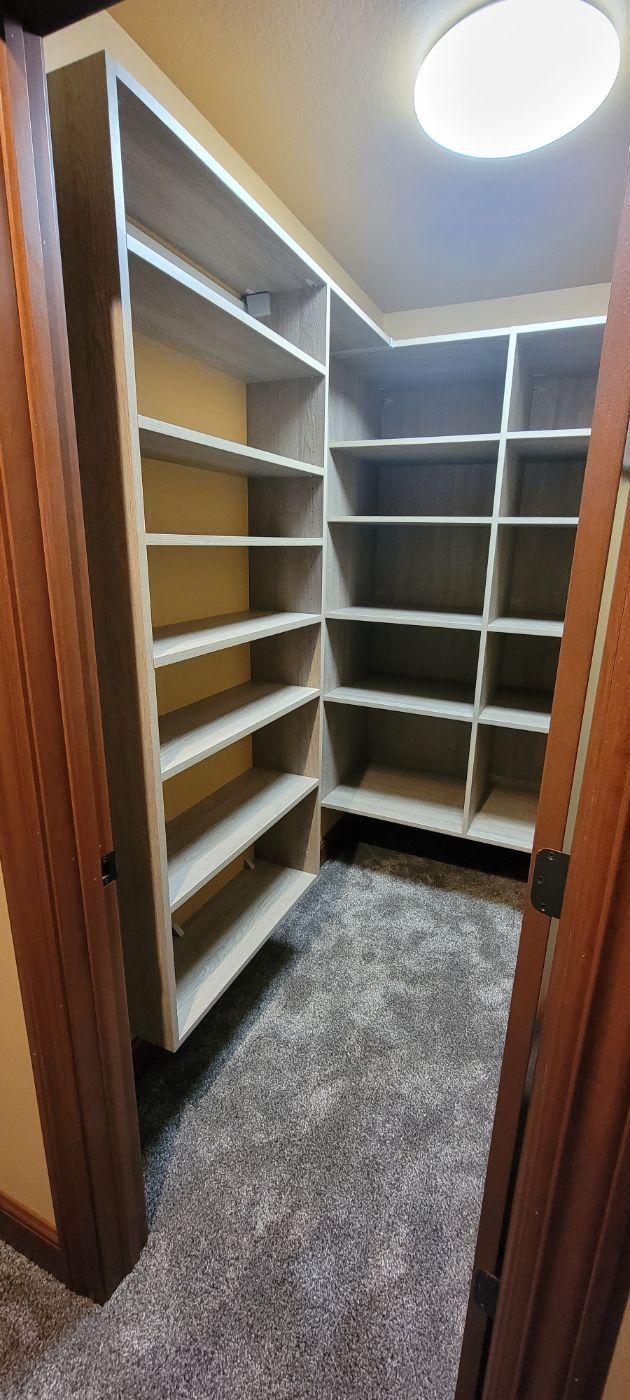 a walk in closet with lots of shelves and a door .
