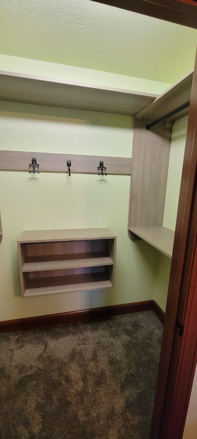 a walk in closet with shelves and hooks on the wall .
