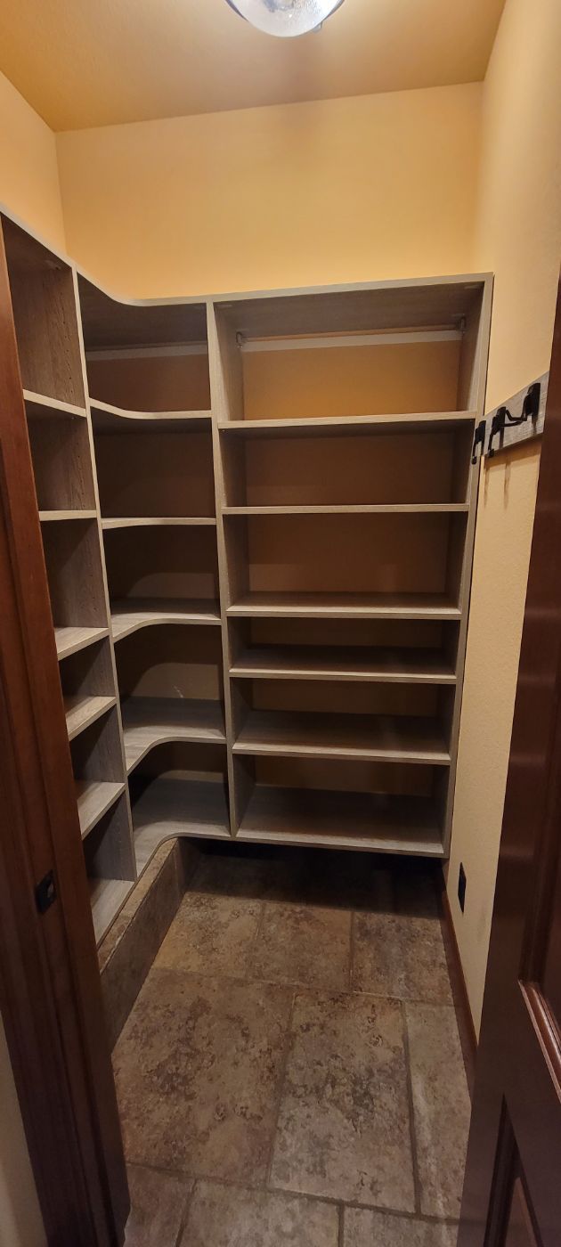 a walk in closet with lots of shelves and a door .