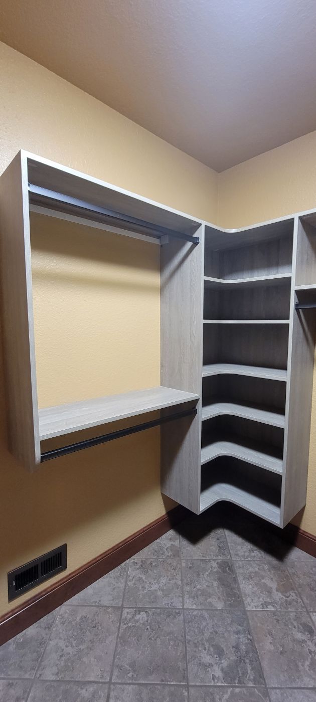 a walk in closet with lots of shelves and clothes racks .