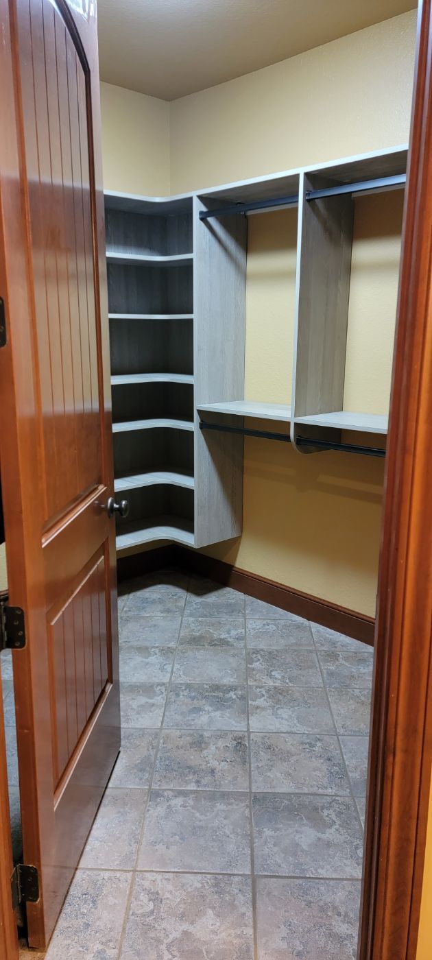 a walk in closet with a wooden door and tile floor .