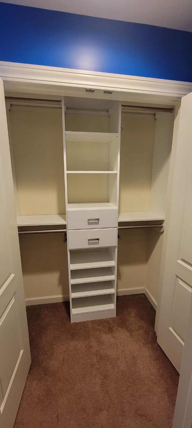 a walk in closet with shelves and drawers and a blue wall .