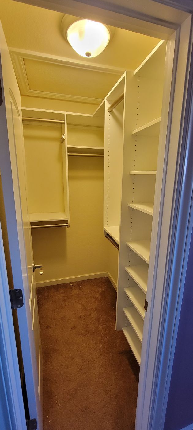 a walk in closet with lots of shelves and a light on the ceiling .