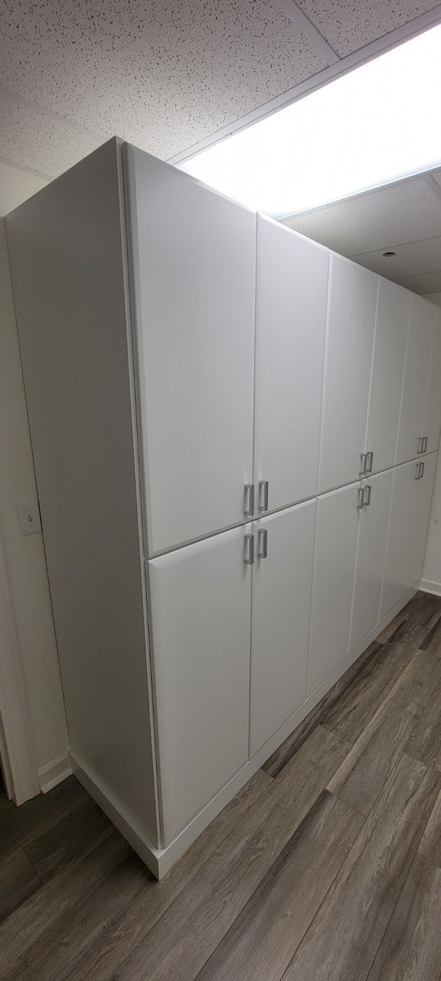 a room with a lot of white cabinets and a wooden floor .