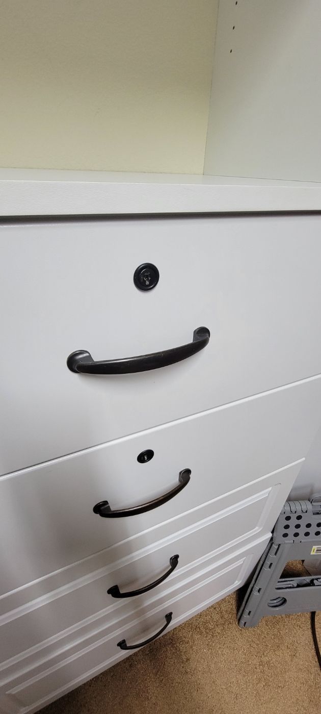 a close up of a white dresser with black handles .