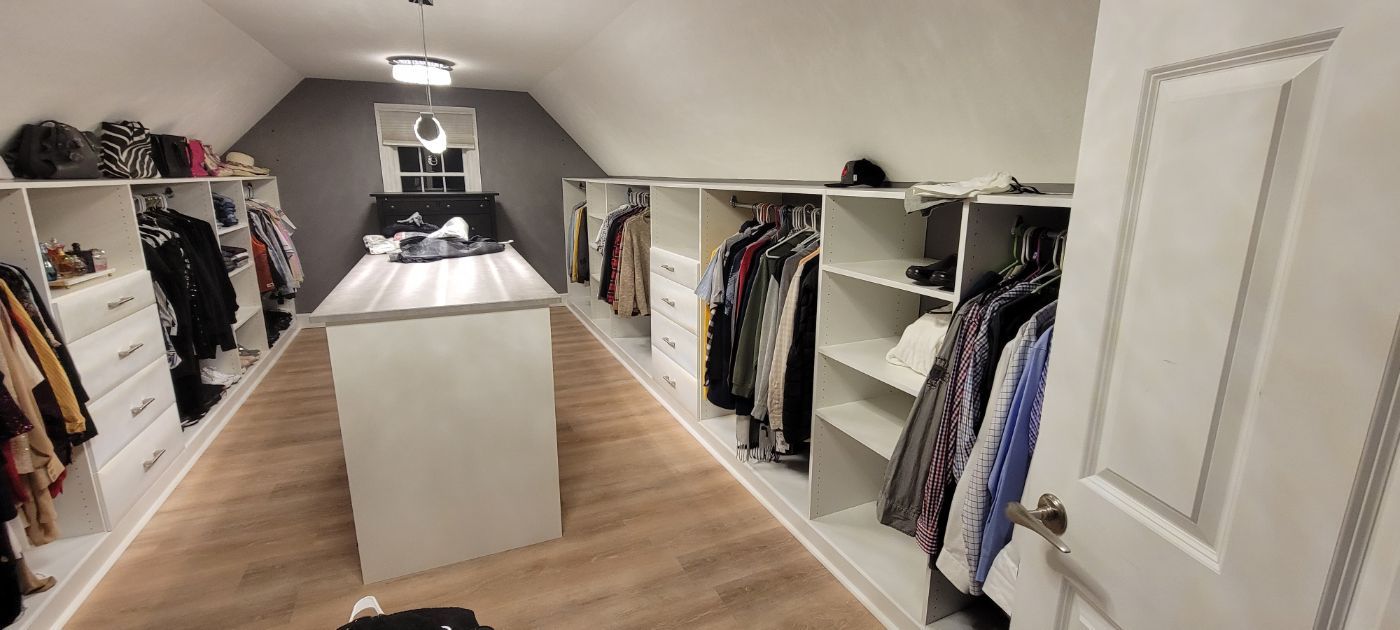 a walk in closet filled with lots of clothes and a table .
