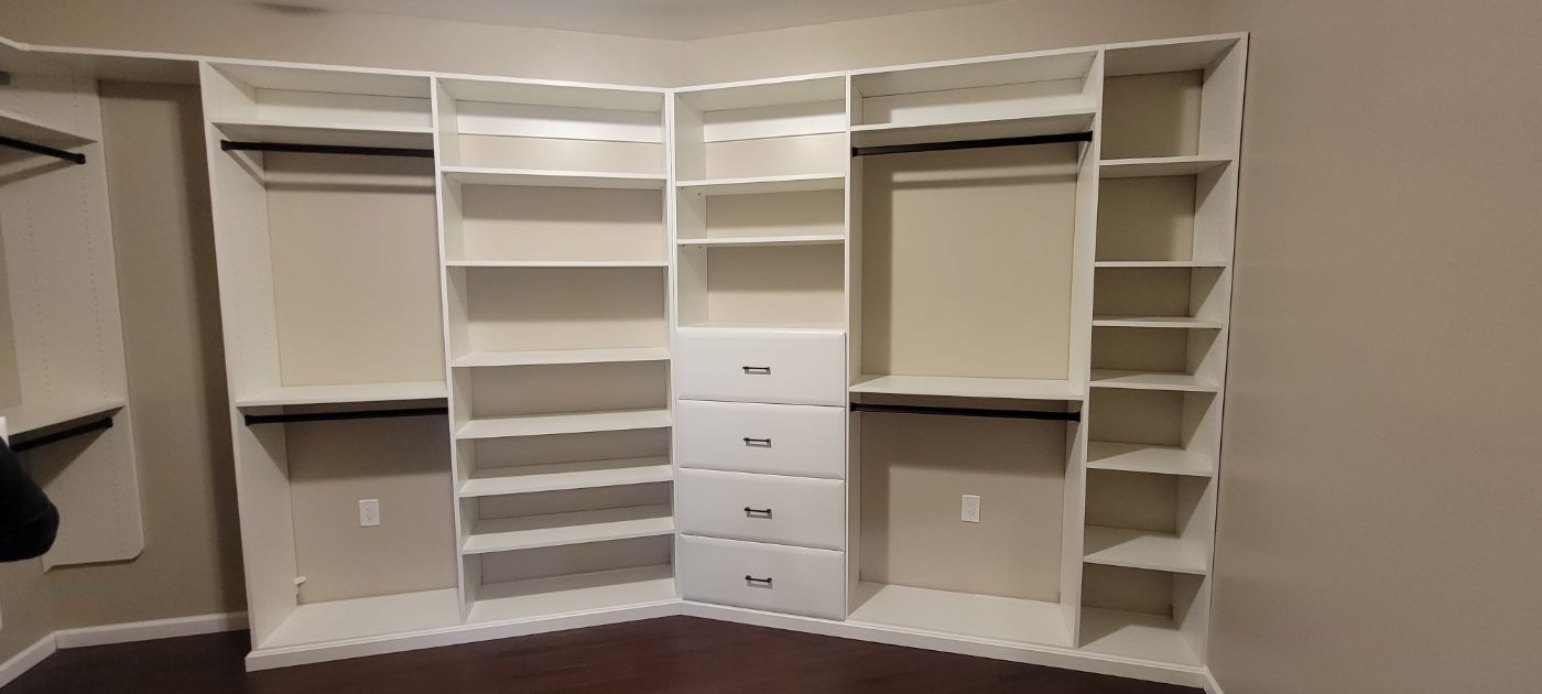 a large walk in closet with lots of shelves and drawers .