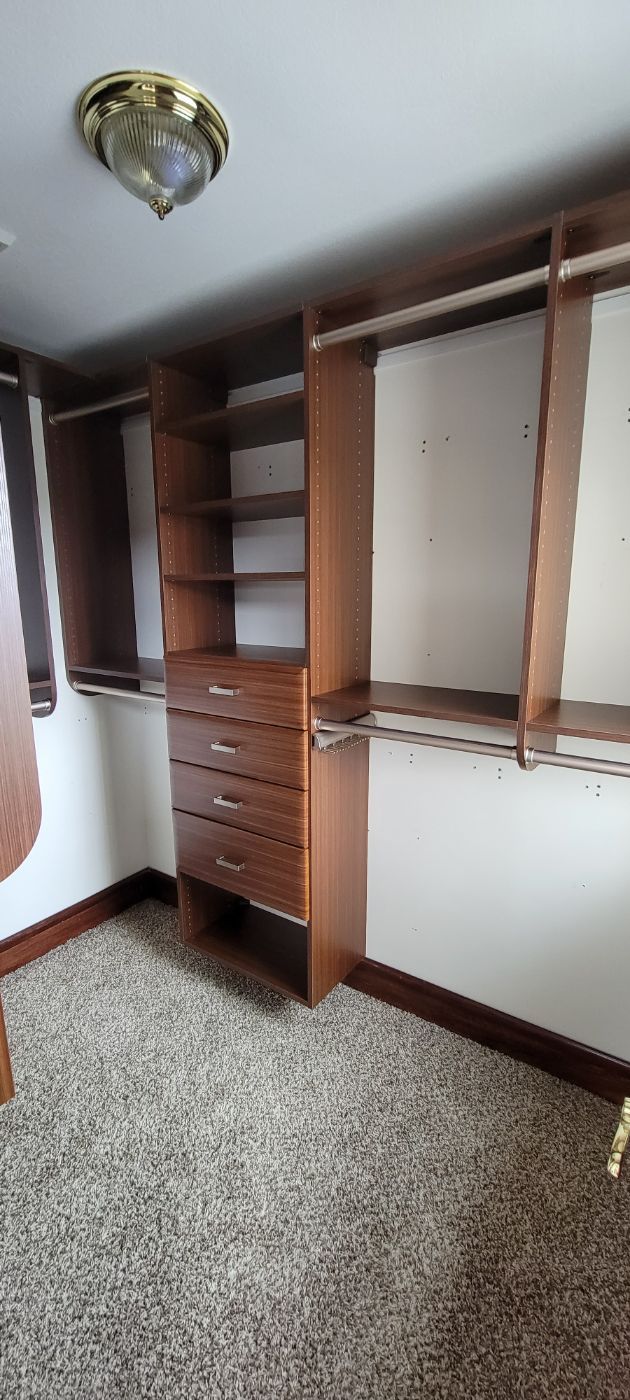 a large walk in closet with lots of shelves and drawers .