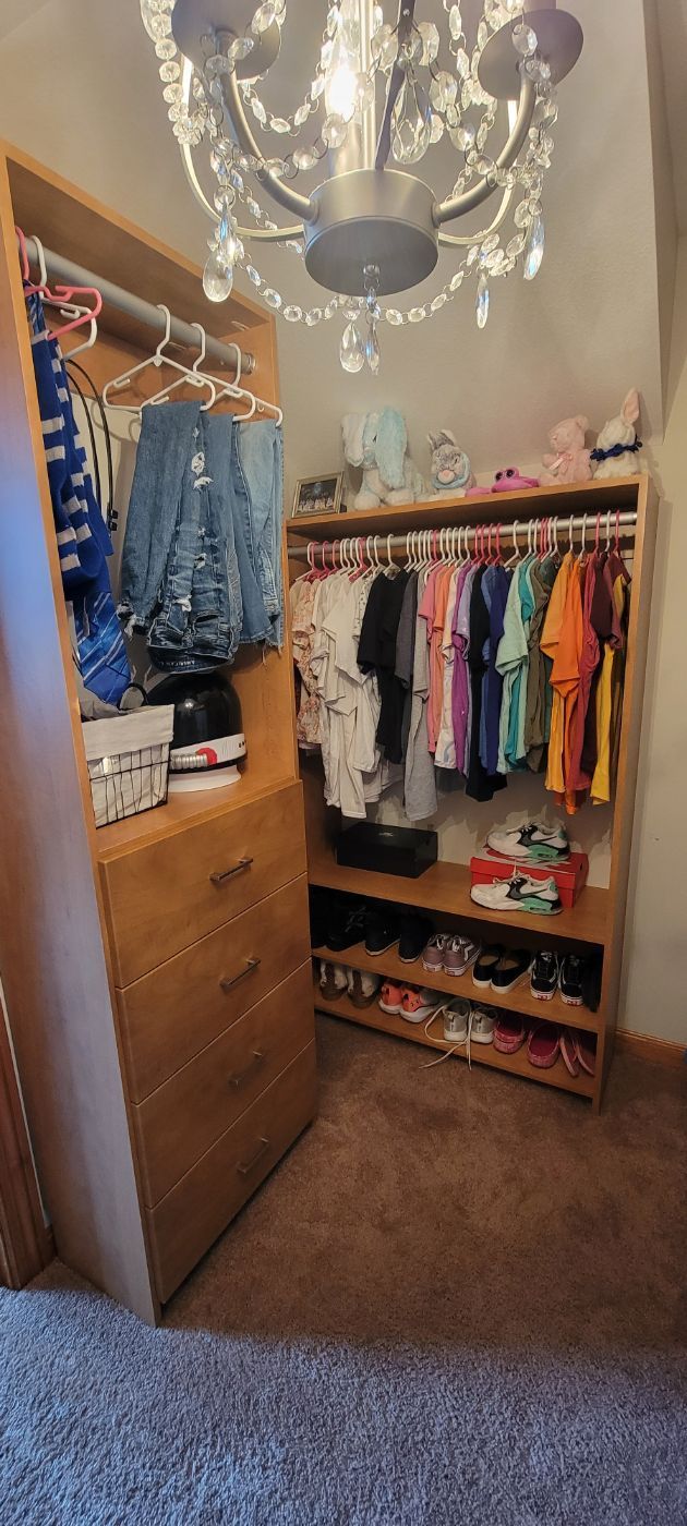 a walk in closet filled with clothes and a chandelier .