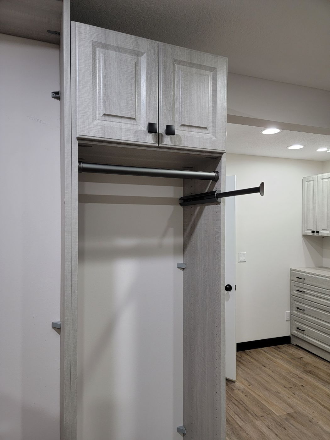 a closet with a hanging rail and cabinets in a room .