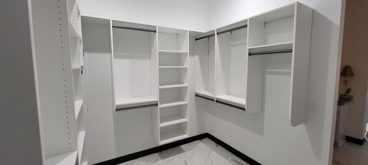 a walk in closet with lots of shelves and hanging racks .