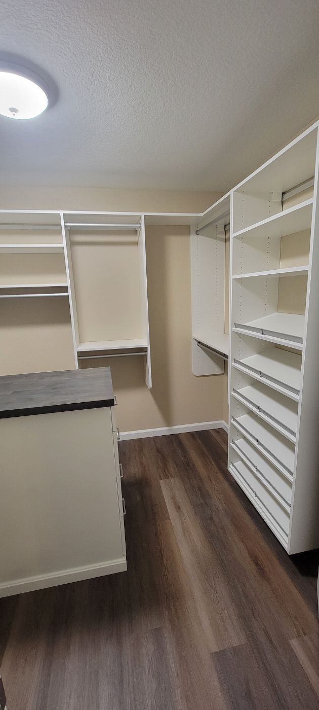 a walk in closet with lots of shelves and a dresser .