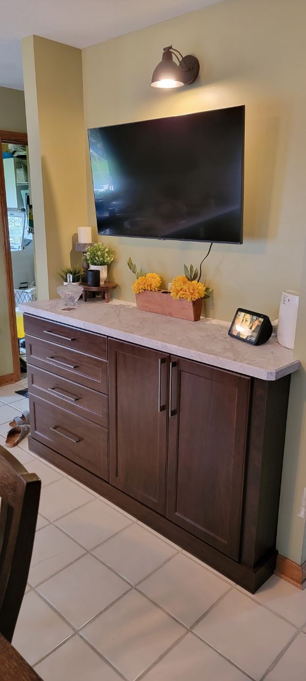 a living room with a dresser and a flat screen tv on the wall .