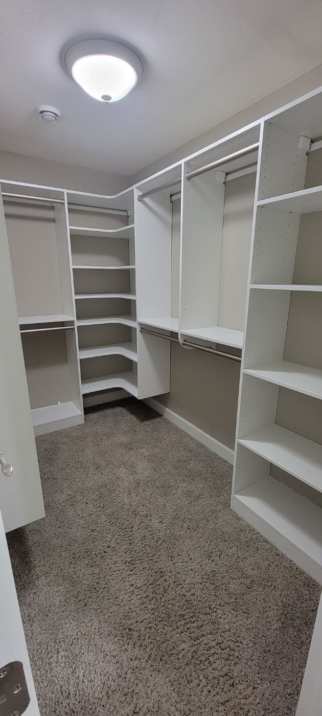a walk in closet with lots of shelves and a light on the ceiling .