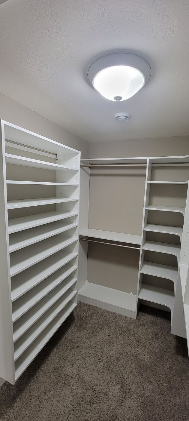 a walk in closet with lots of shelves and a light on the ceiling .