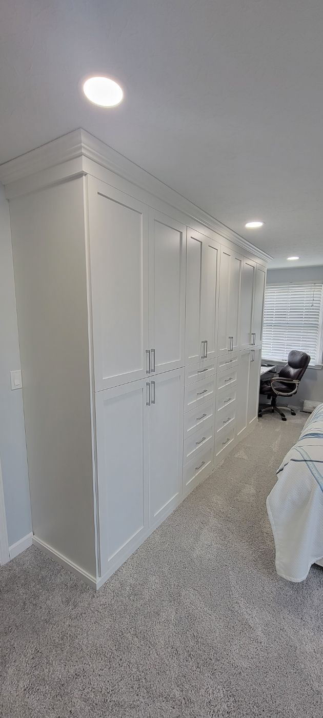 a bedroom with a lot of white cabinets and drawers .